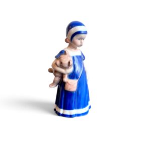 Statuina Elsa in porcellana Royal Copenhagen raffigurante una bambina con vestito blu che tiene un orsetto